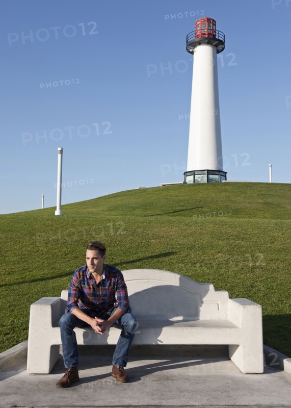 Man sitting on park bench near lighthouse