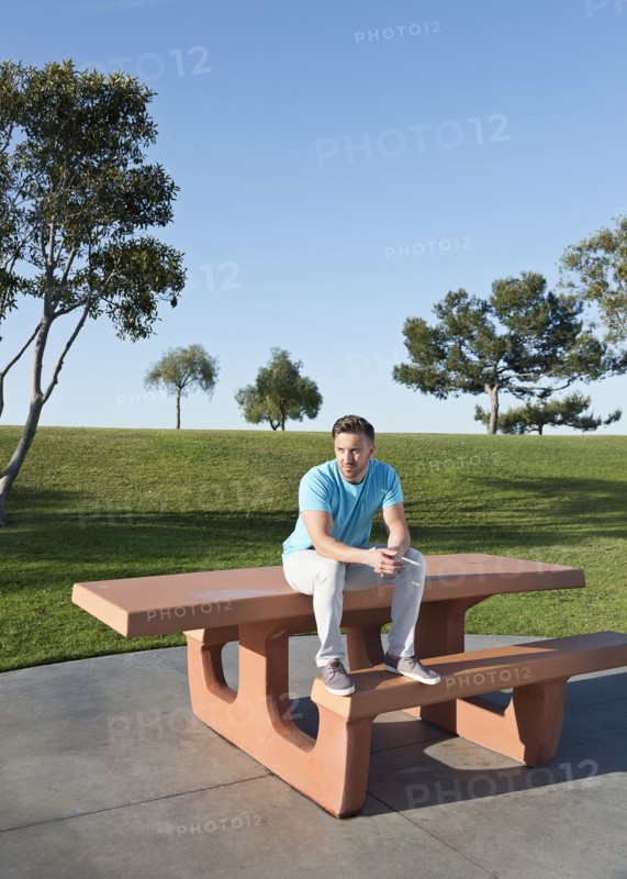 Caucasian man sitting on picnic table in park