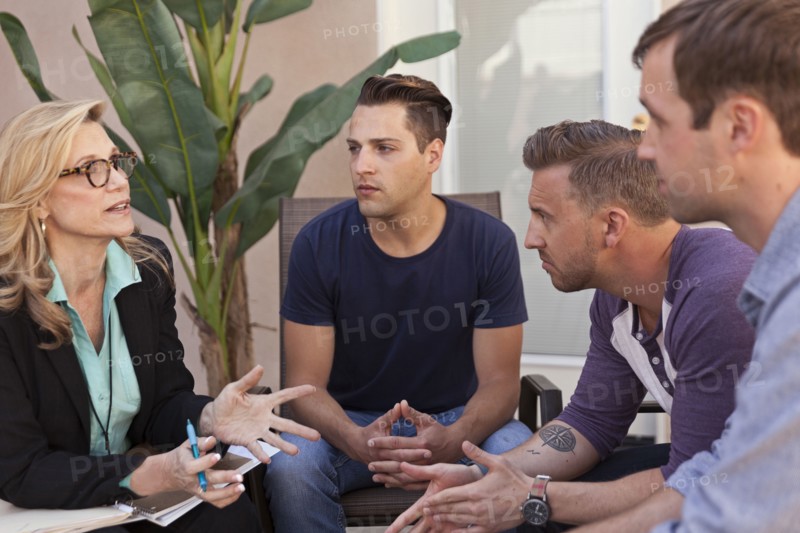 Men talking with therapist in group therapy