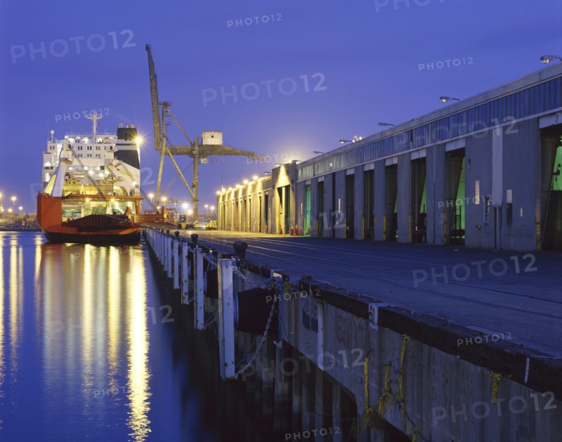 Cargo ship under crane in harbor at night