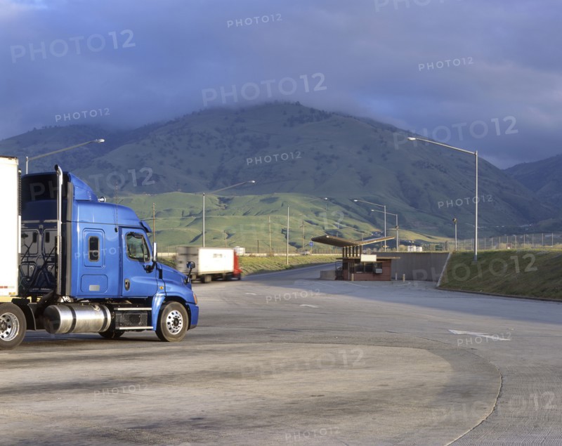 Blue semi-truck following arrows on road