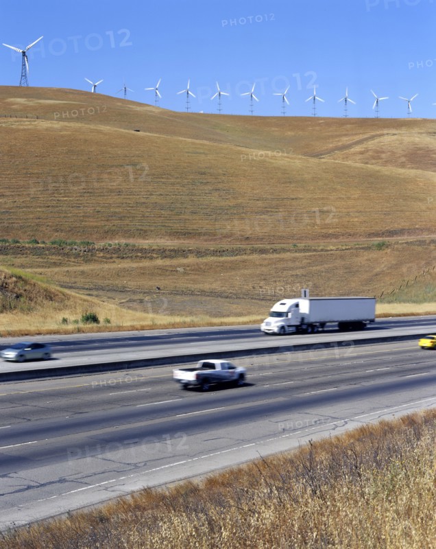 Cars and trucks driving on freeway near wind farm