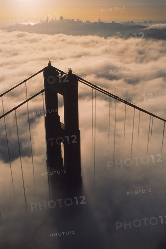 Aerial view of bridge over fog at sunset