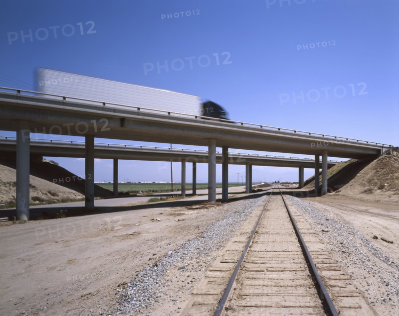 Trucks driving on freeway overpass over train track