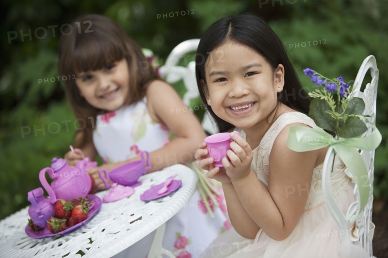 Mixed race girls having tea party in backyard