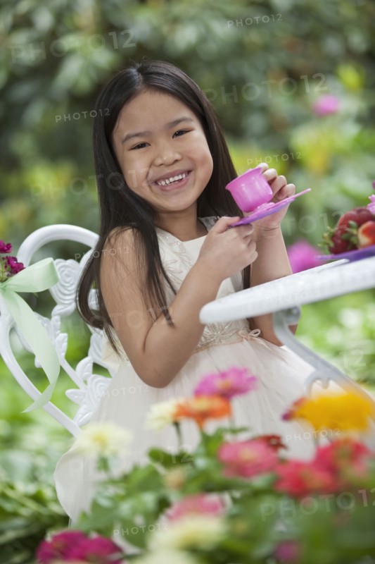 Mixed race girl having tea party in backyard