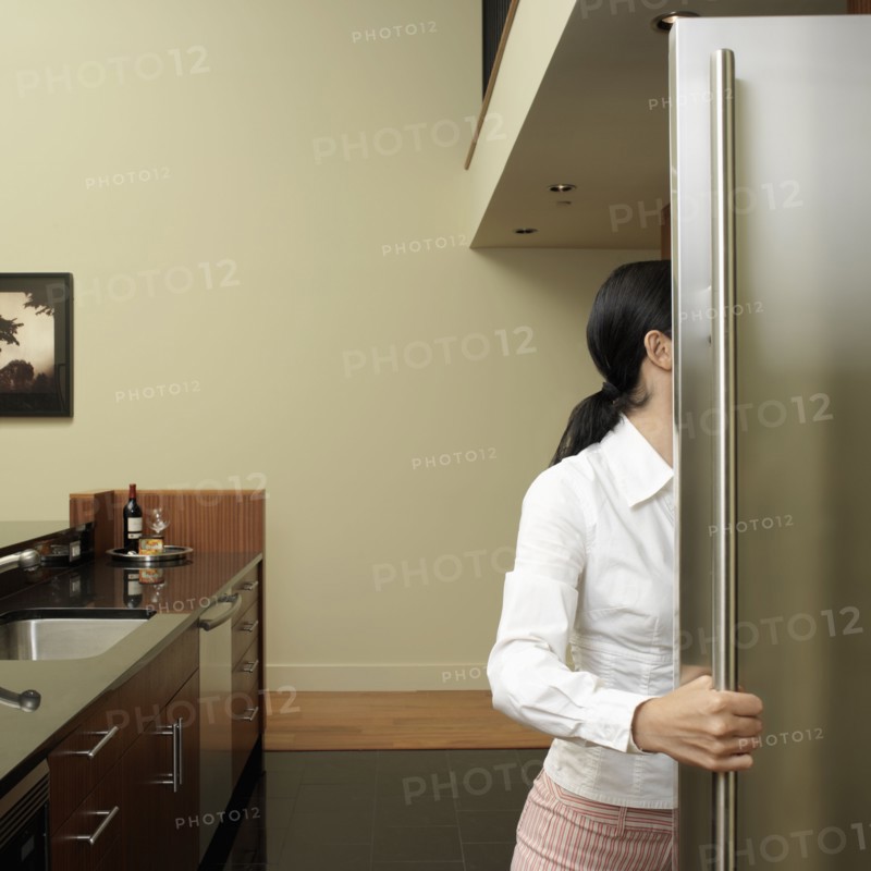 Asian woman looking in refrigerator