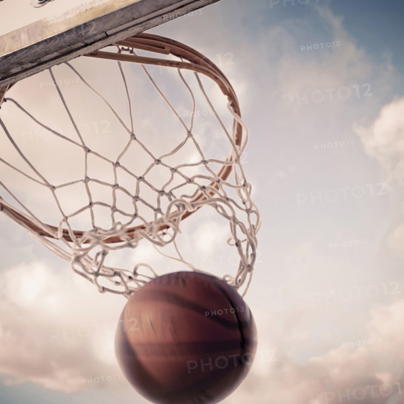 Basketball falling through hoop on court