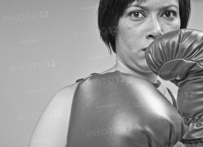 Mixed race boxer holding gloves in front of face