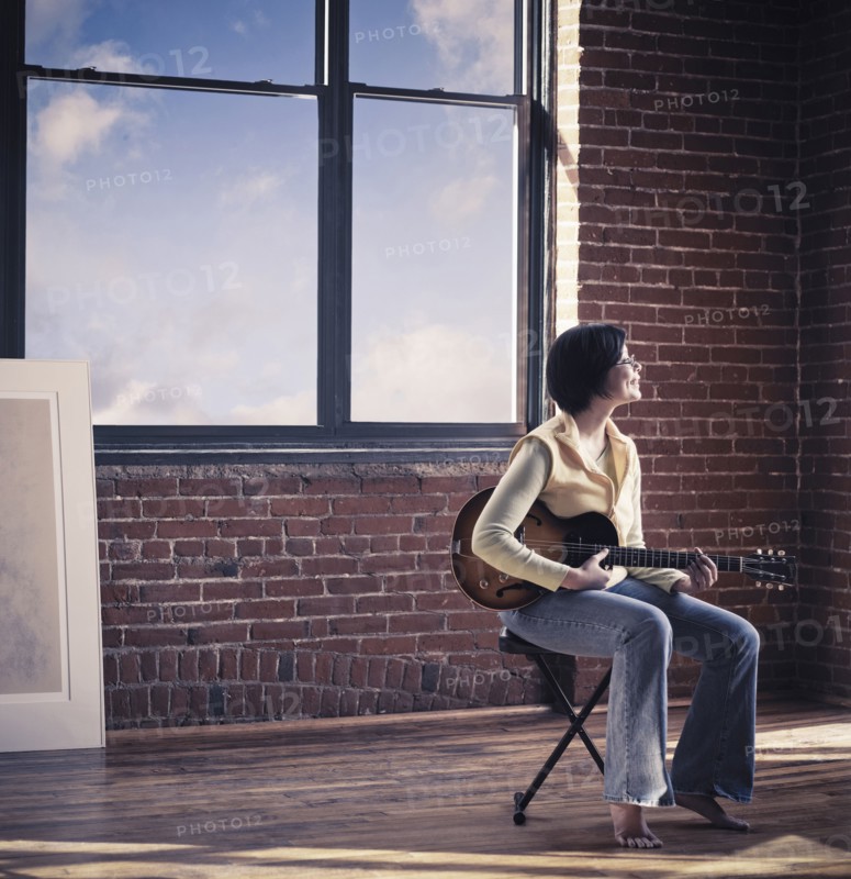 Caucasian woman playing guitar in living room