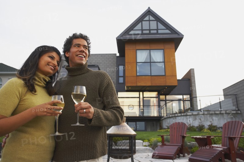 Couple holding wine in front of house
