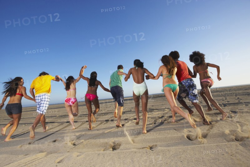 Multi-ethnic group of friends running on beach