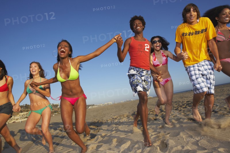 Multi-ethnic group of friends running on beach