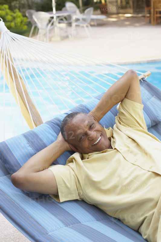 African man laying in hammock at poolside