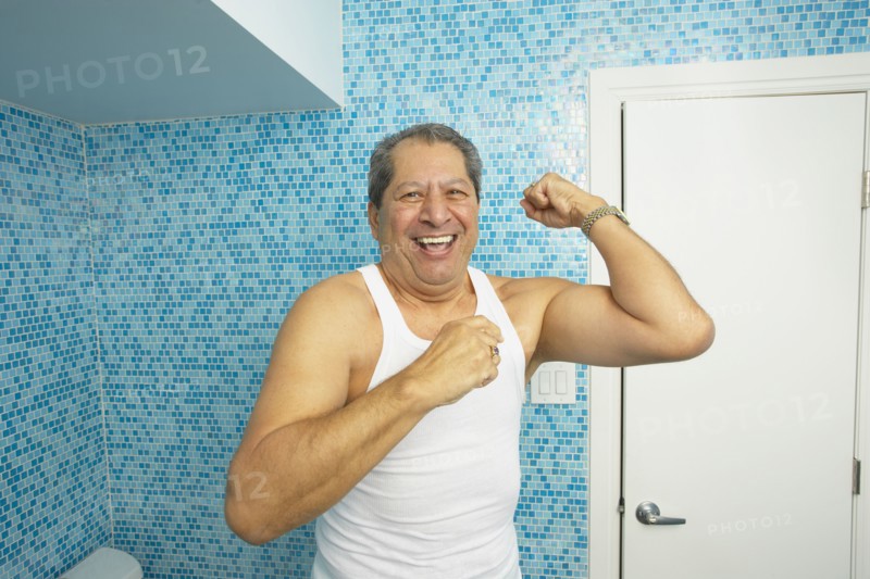 Hispanic man flexing his biceps in bathroom