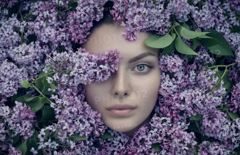 Face of Caucasian woman surrounded by purple flowers