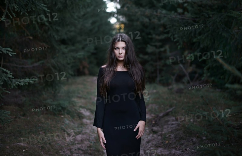 Caucasian woman wearing black dress in forest