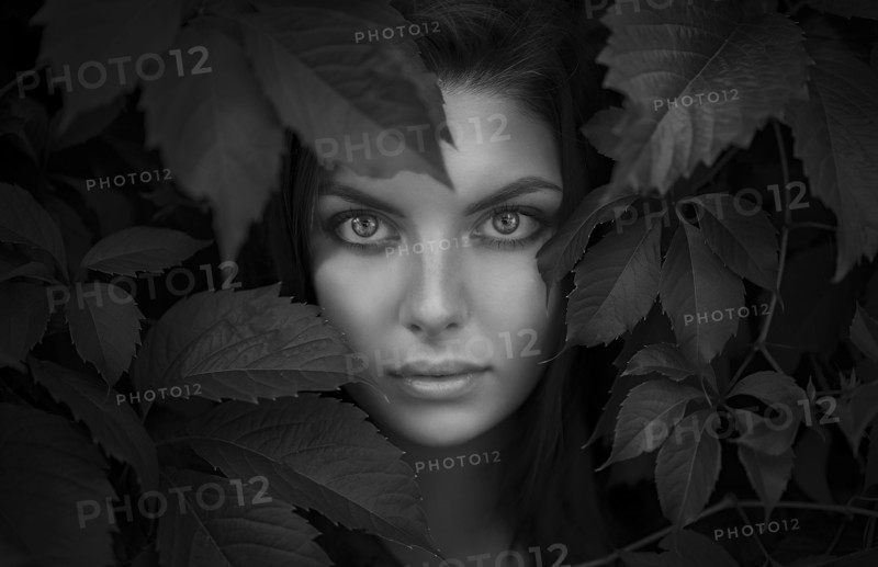 Face of Caucasian woman behind foliage