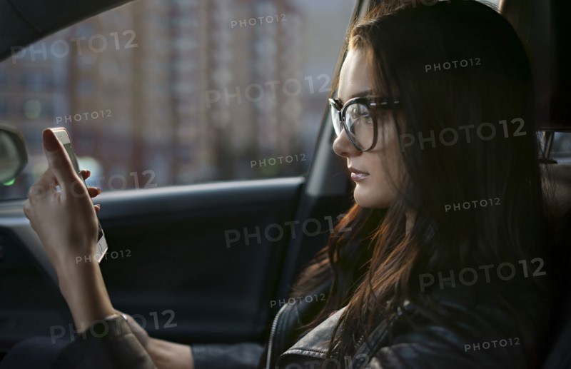 Caucasian woman sitting in car texting on cell phone