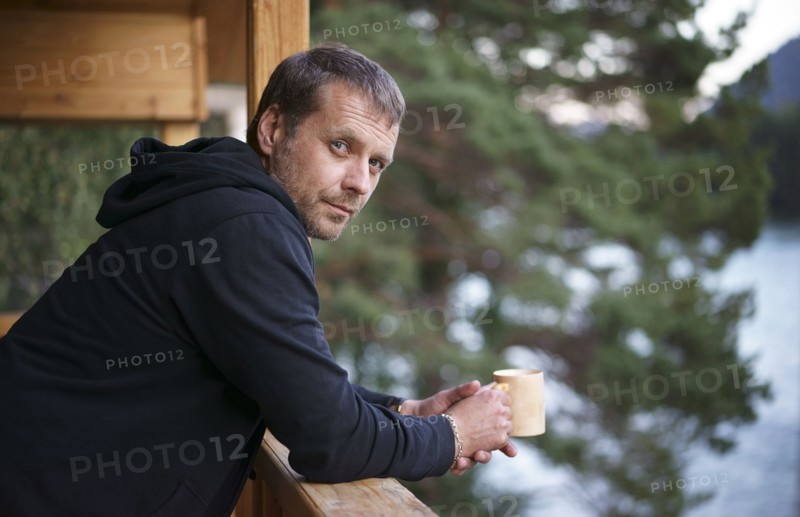 Caucasian man leaning on railing drinking coffee
