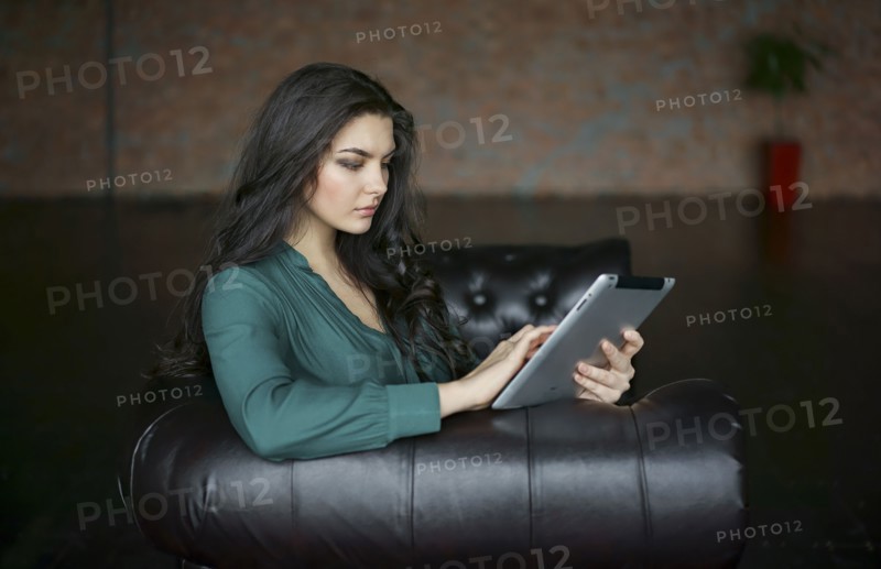 Caucasian businesswoman sitting on sofa using digital tablet