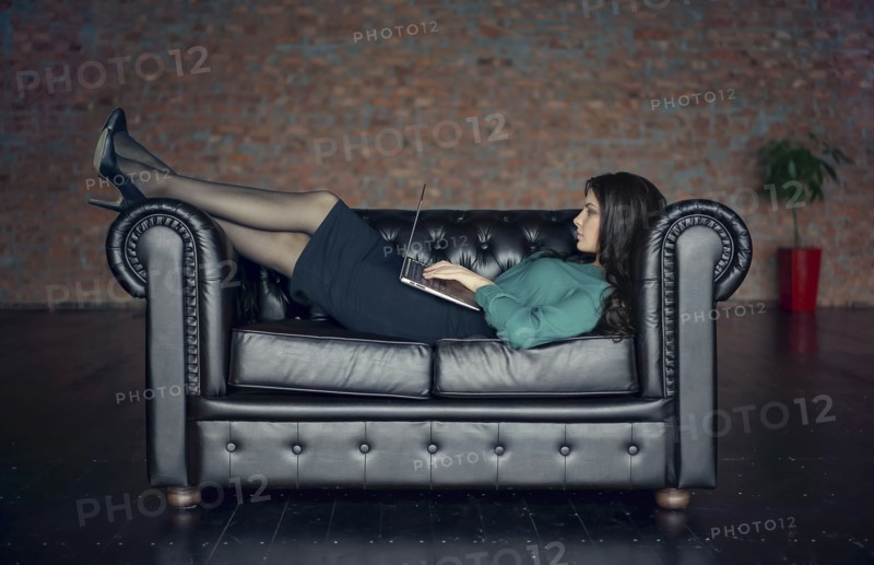 Caucasian businesswoman laying on sofa using digital tablet