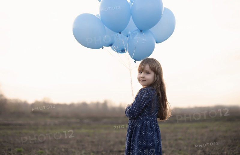 Caucasian girl holding blue helium balloons