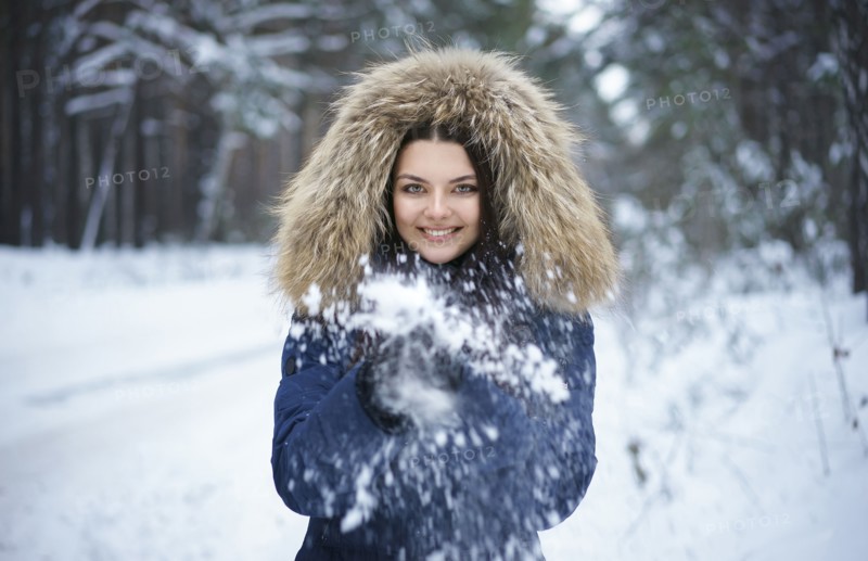 Portrait of playful Caucasian woman throwing snow