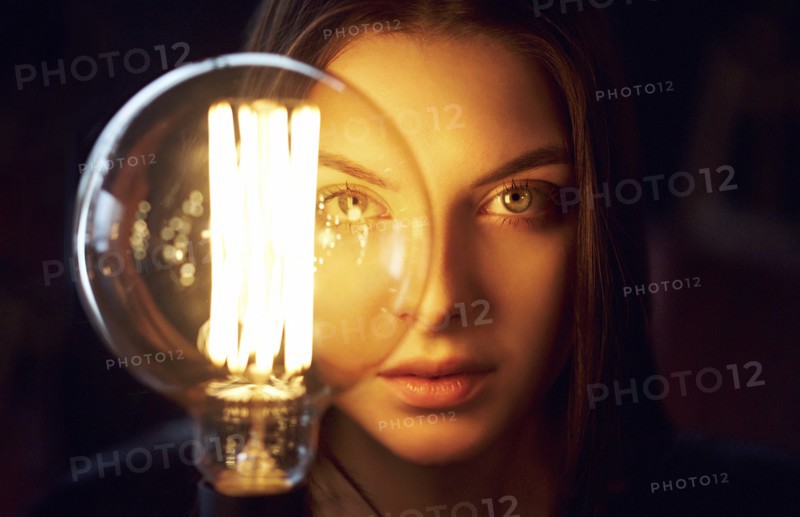 Face of Caucasian woman illuminated by energy efficient light bulb