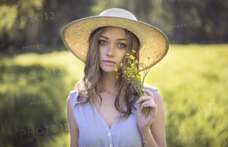 Caucasian woman wearing hat holding wildflowers