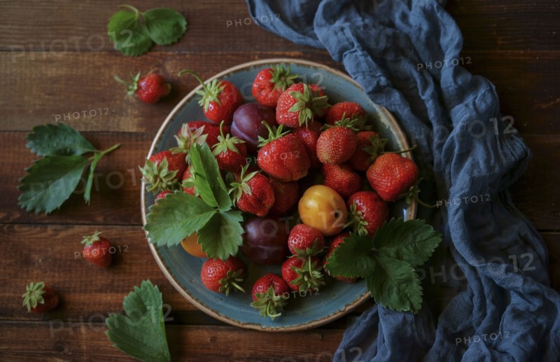 Strawberries and plums on plate