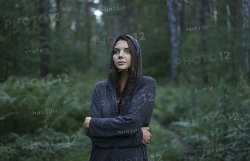 Cold Caucasian woman standing in forest