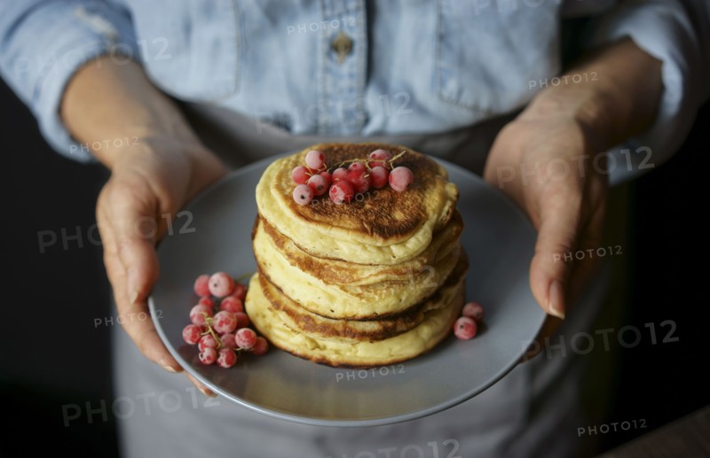 Close up of Caucasian woman holding plate of pancakes