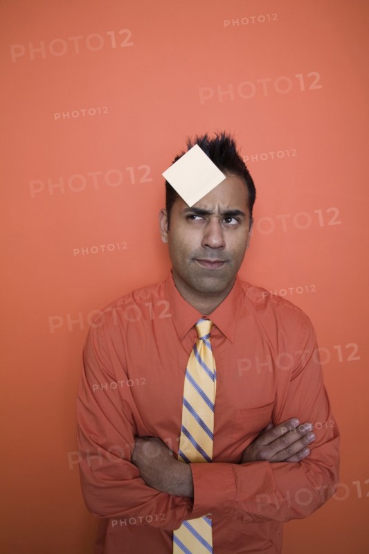 Mixed race businessman with sticky note on forehead