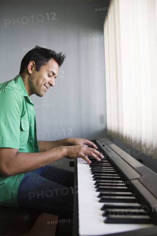 Mixed race man playing electric keyboard