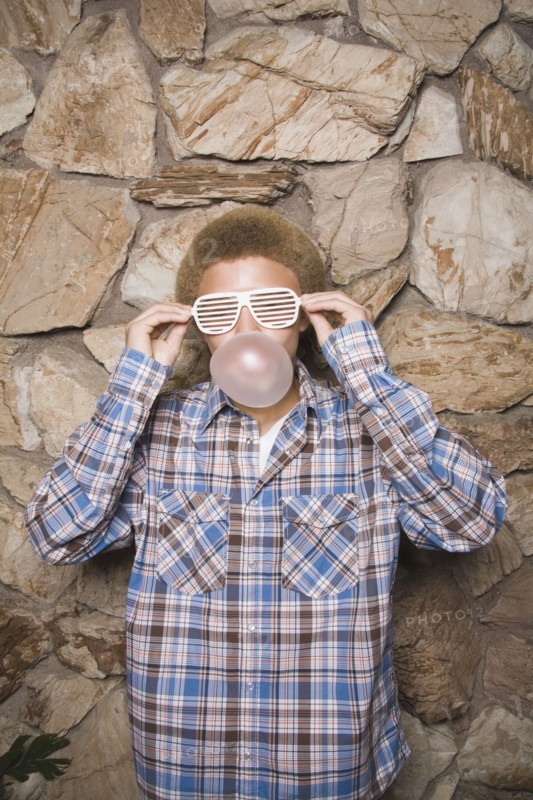Mixed race boy in sunglasses chewing bubble gum
