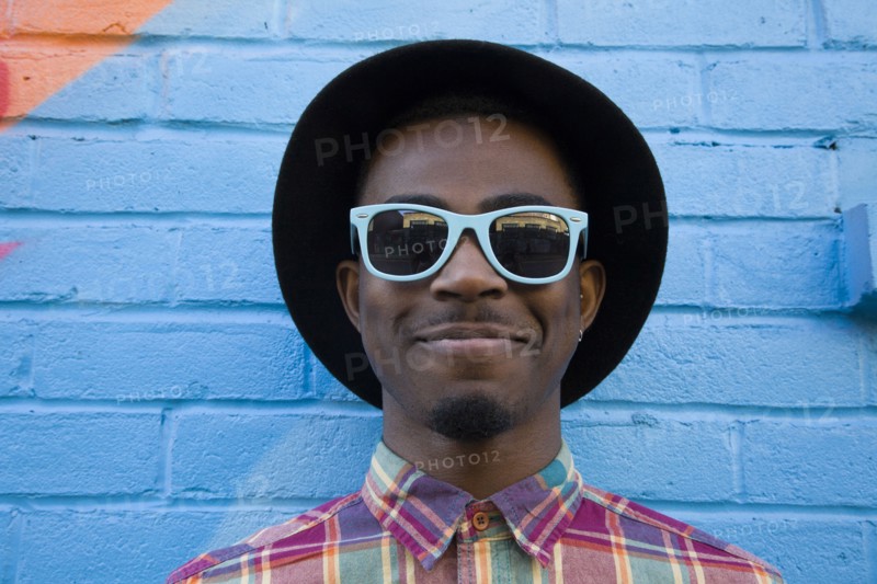 Black man wearing sunglasses near colorful wall