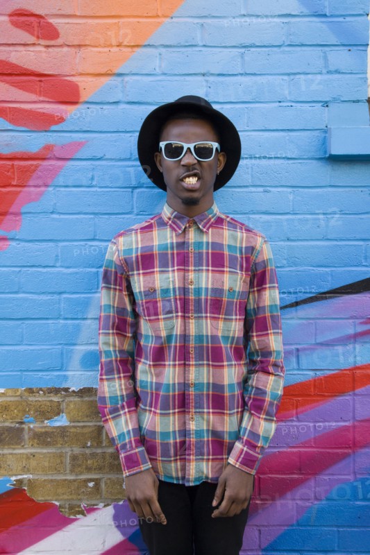 Black man wearing sunglasses near colorful wall