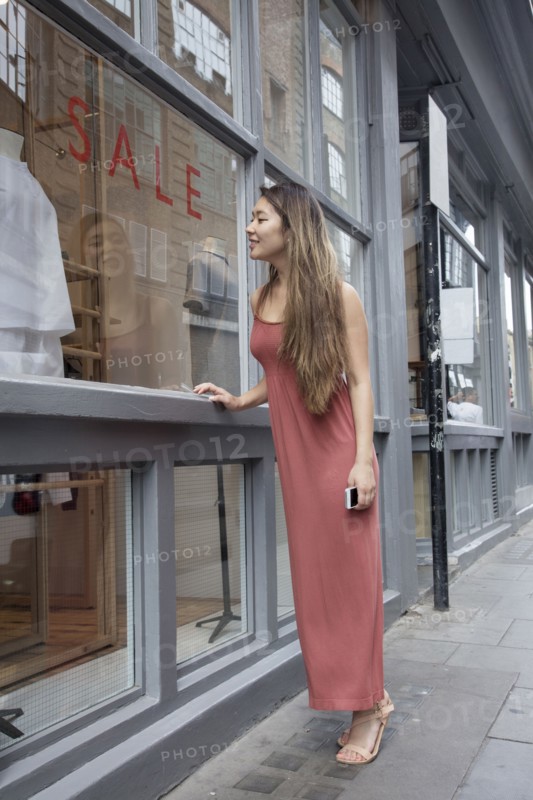 Asian woman window shopping outside store