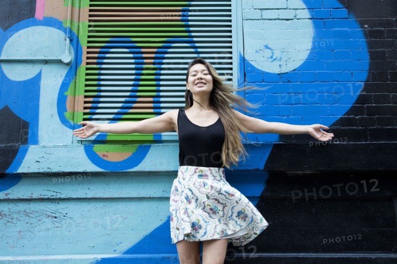 Asian woman cheering with arms outstretched