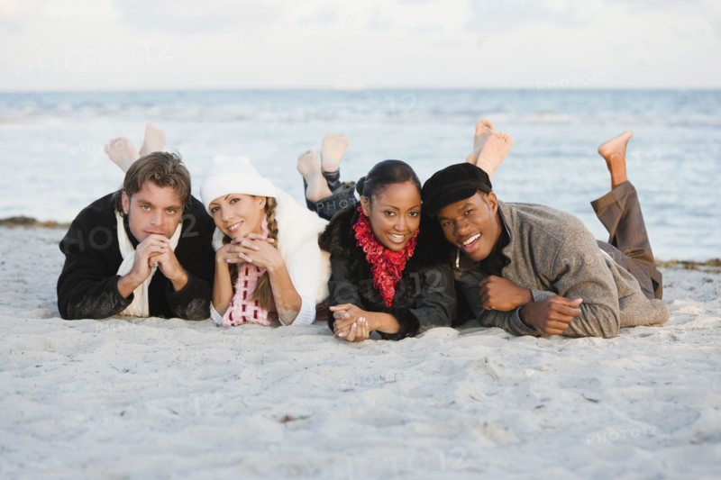 Multi-ethnic couples laying on beach
