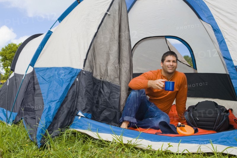 Hispanic man drinking coffee in tent