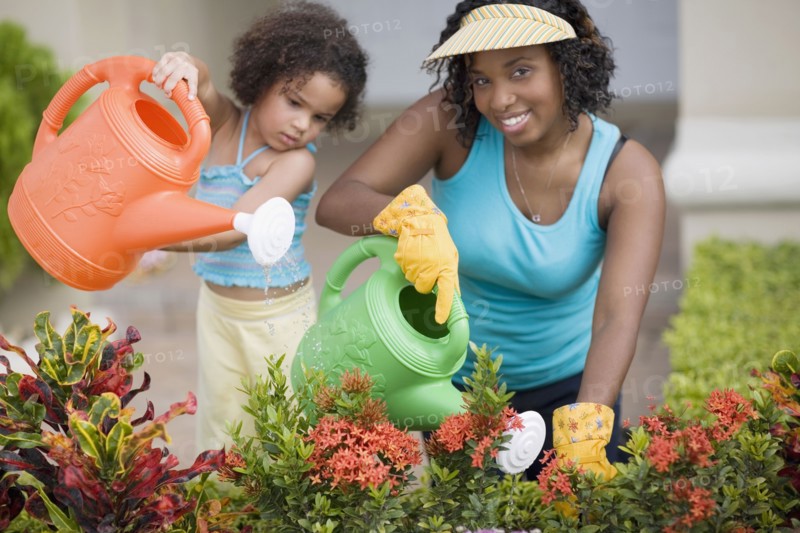 African mother and daughter watering flowers