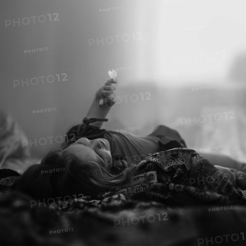 Caucasian girl laying on blanket with butterfly on finger