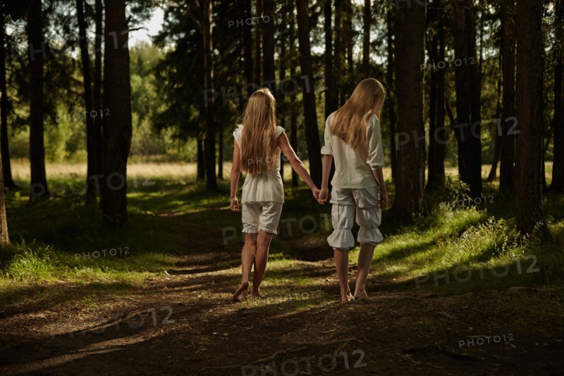 Caucasian girls holding hands in forest
