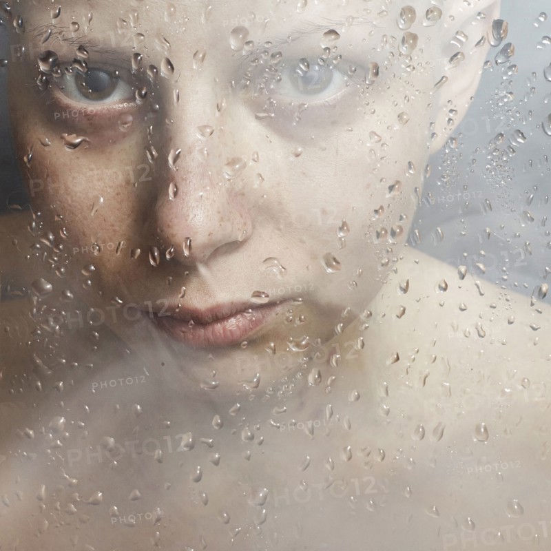 Caucasian woman peering through wet glass