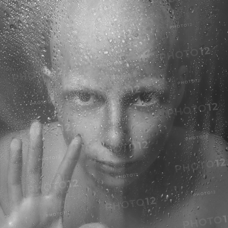Caucasian woman peering through wet glass