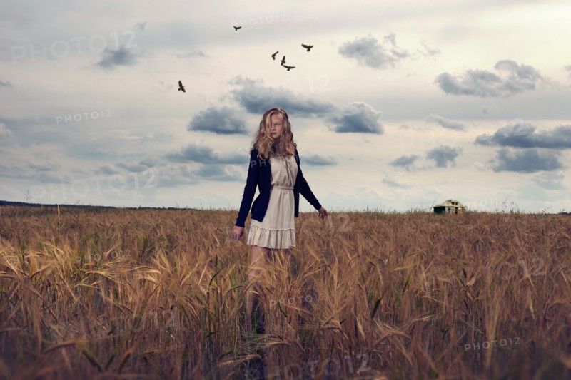 Caucasian teenage girl standing in field of tall grass