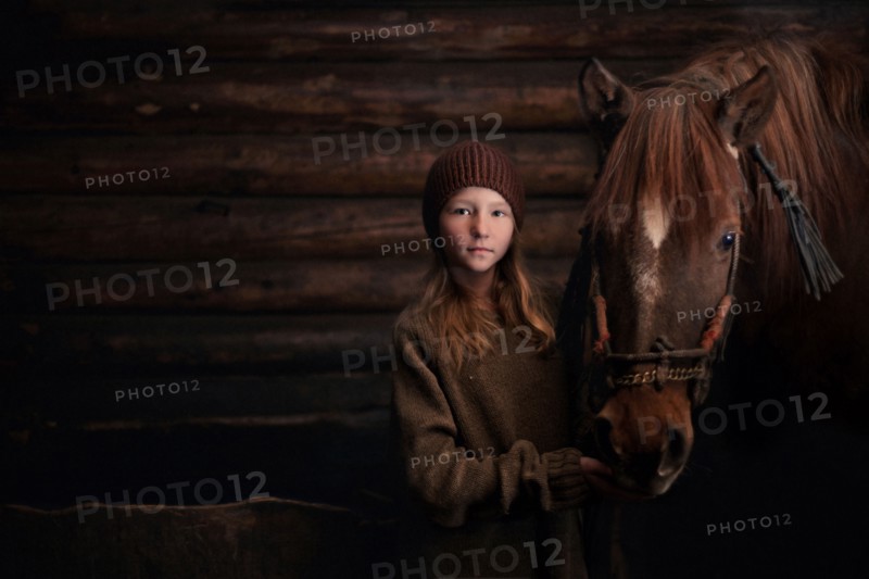 Caucasian girl standing with horse in barn