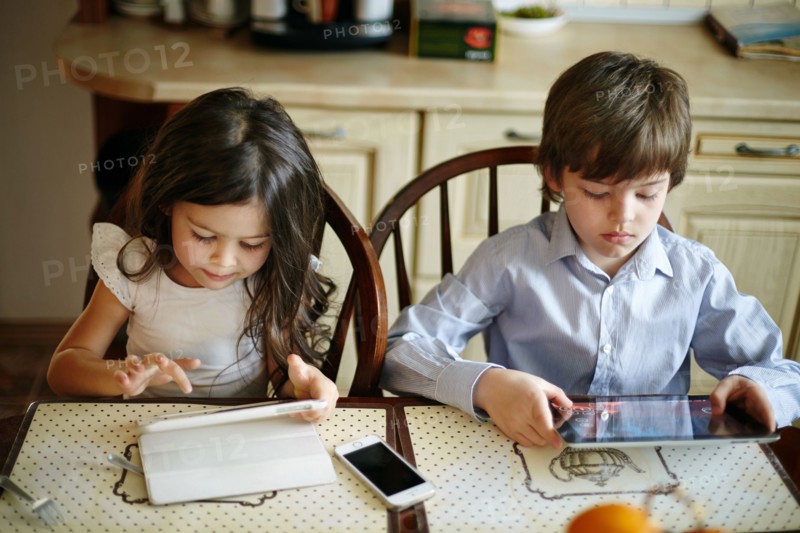 Caucasian brother and sister using digital tablets